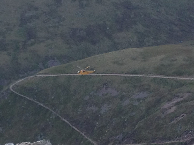 A rescue helicopter flying in the valley below