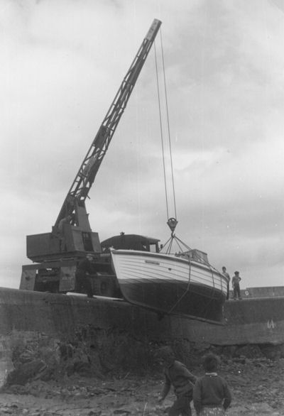 The crane lowers the boat, named 'Constancy', in to the inner harbour at low tide The crane lowers the boat, named 'Constancy', in to the inner harbour at low tide